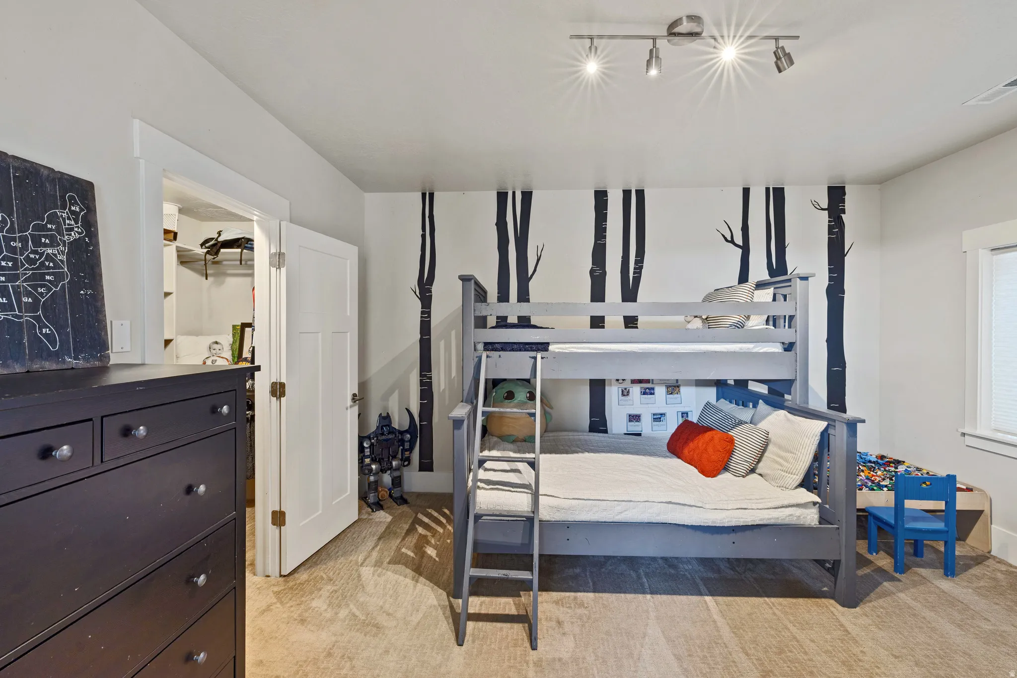 Bedroom featuring carpet, a white trim window with blinds, and accent wall