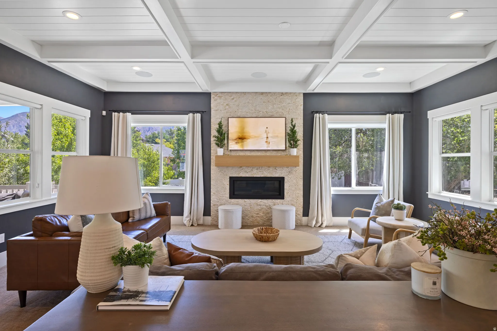 Spacious living area featuring a coffered ceiling, recessed lighting, and a stone-clad fireplace with a wood mantel
