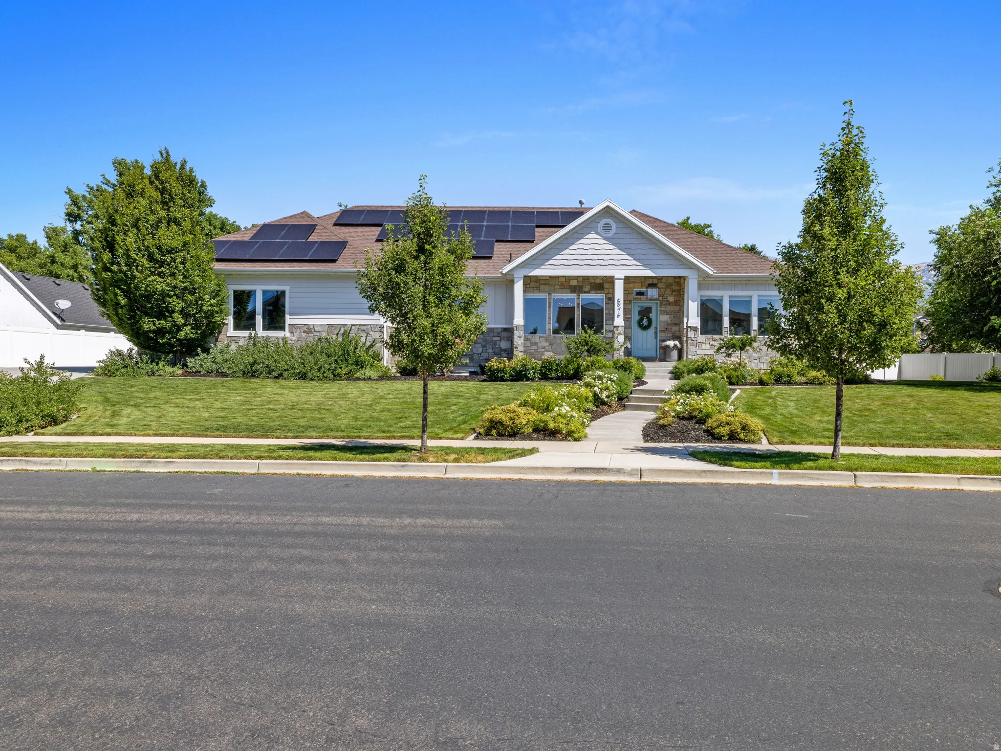 Ranch-style exterior with stone and siding facade, a covered entry porch, and a concrete pathway