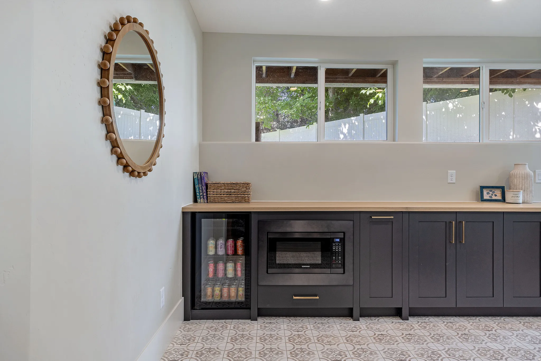 Kitchenette and study room - Versatile lower-level space featuring patterned floor tiles, a built-in desk area  with under-counter storage, and a separate cabinet run with a wood-finish countertop. Basement entrance to the backyard is an added bonus.