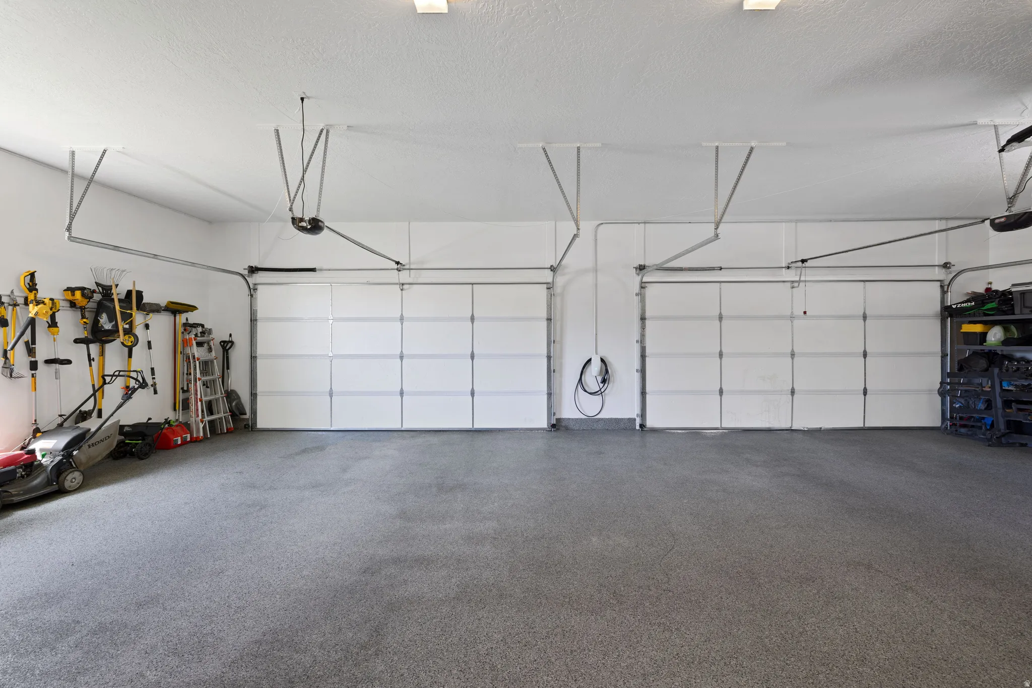 4 car garage featuring a speckled epoxy floor coating, overhead garage door openers, and bright overhead lighting