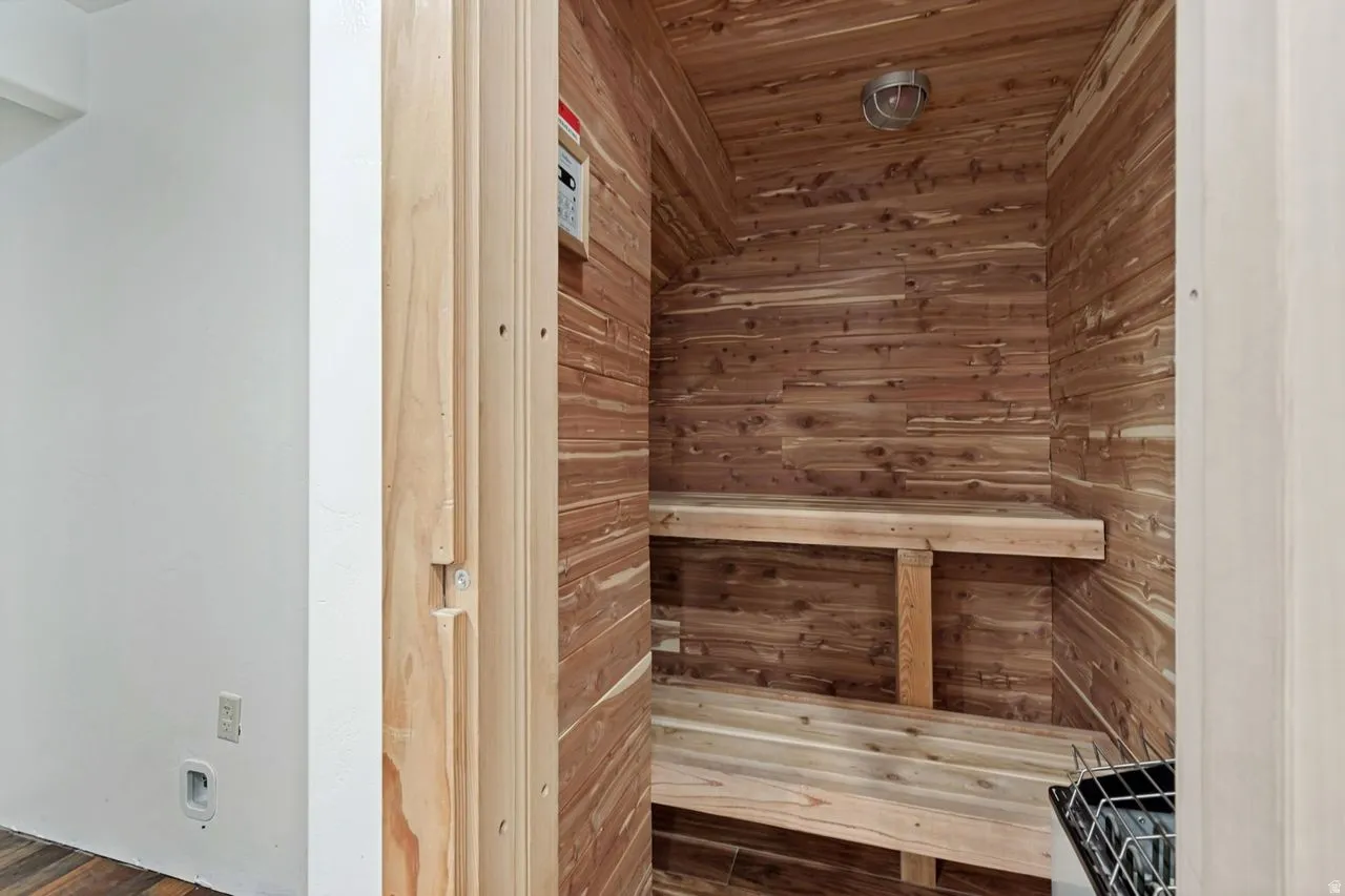 Dedicated sauna featuring natural wood paneling, multi-level wooden benches, a ceiling-mounted light fixture, and a built-in heating unit