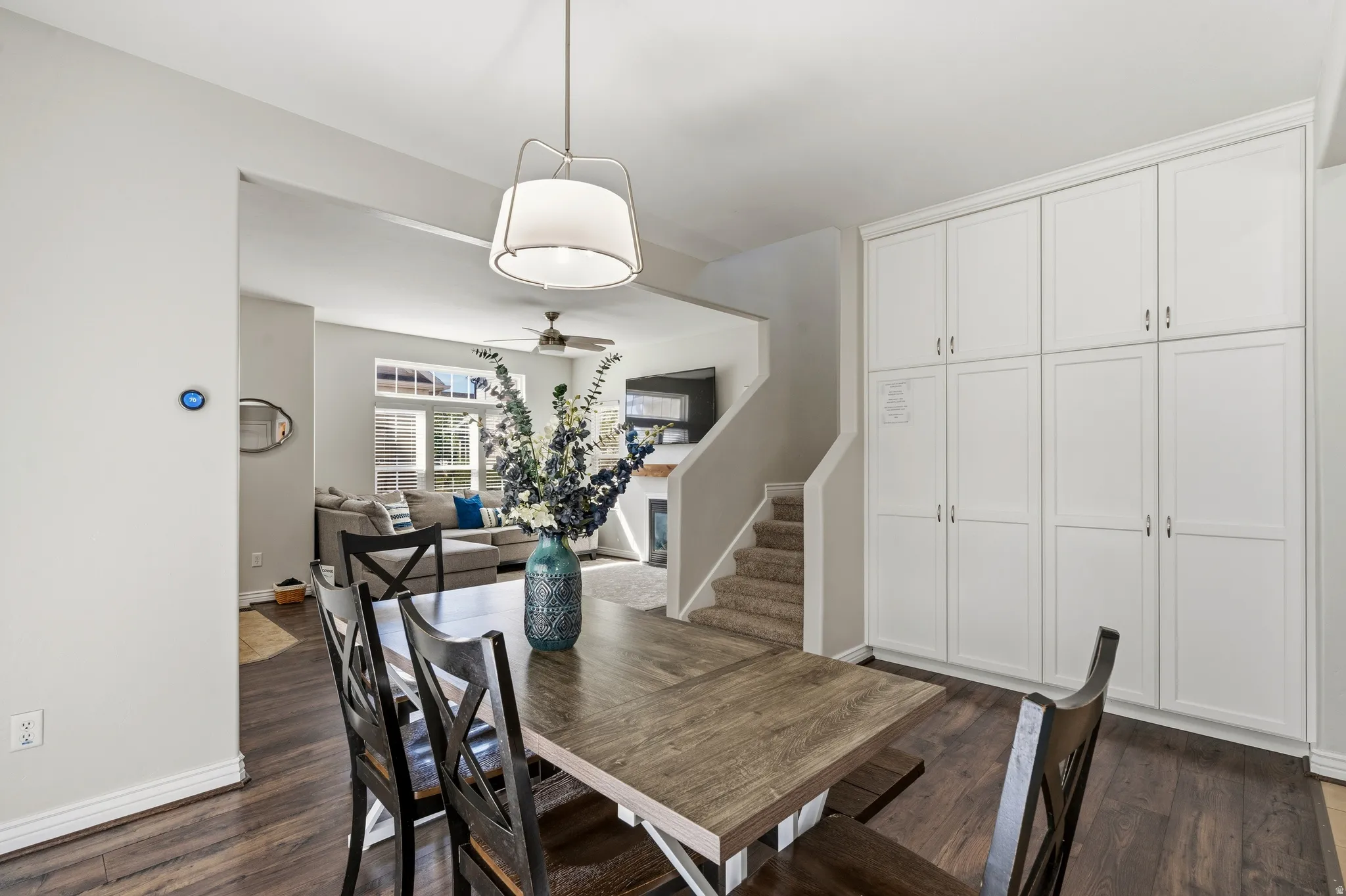 Hardwood-finish flooring, built-in white panel cabinetry, contemporary pendant lighting, and an open concept layout