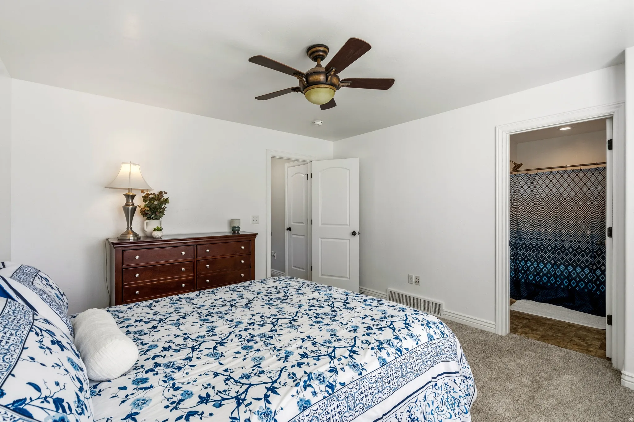 White painted walls, ceiling fan, carpeted flooring, and a built-in closet
