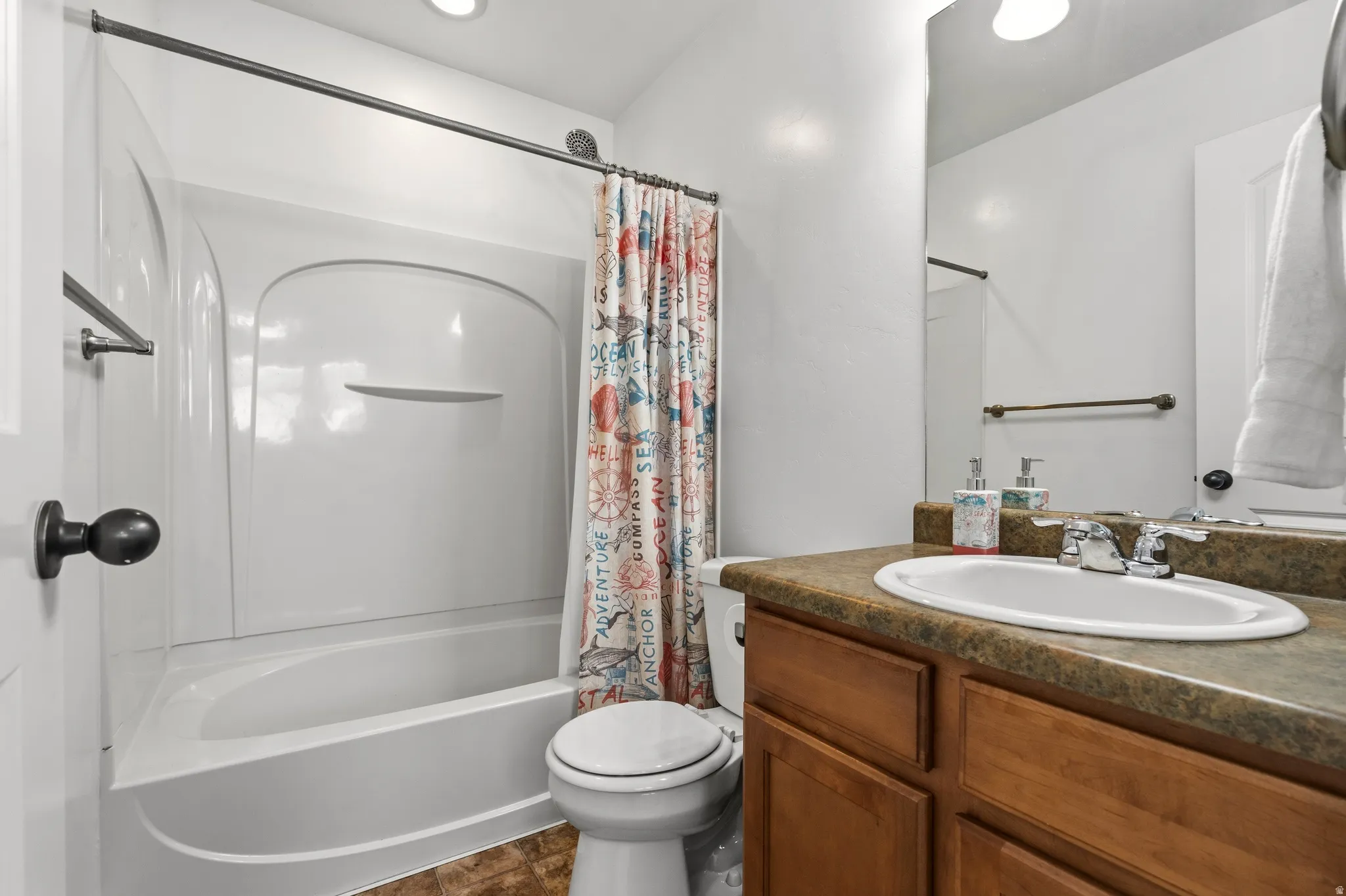 Bathroom with an integrated tub and shower unit, wood-finish vanity, and a drop-in sink