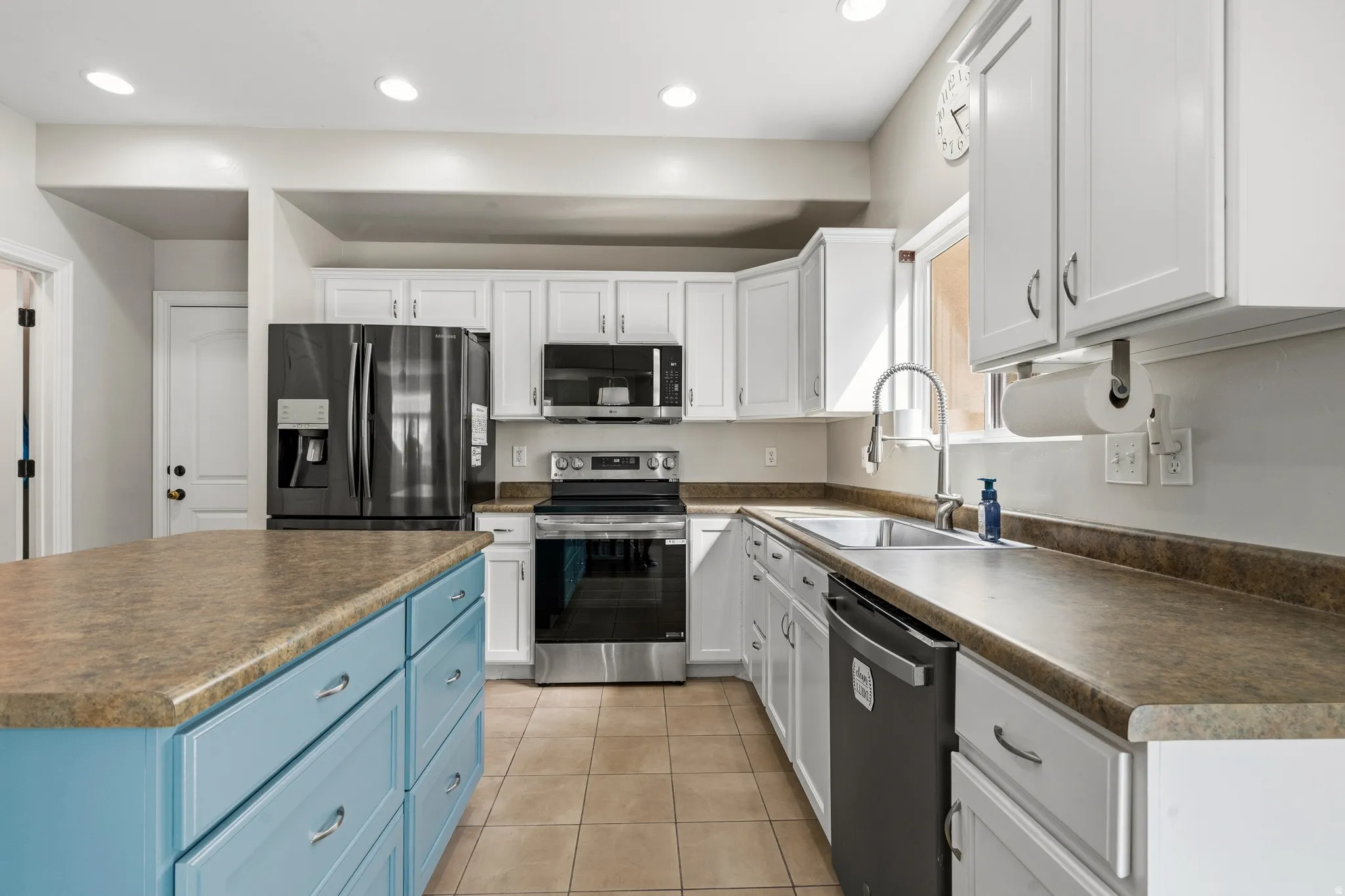 Chef's kitchen featuring white cabinetry with stainless steel appliances, including a French-door refrigerator, gas range, and microwave