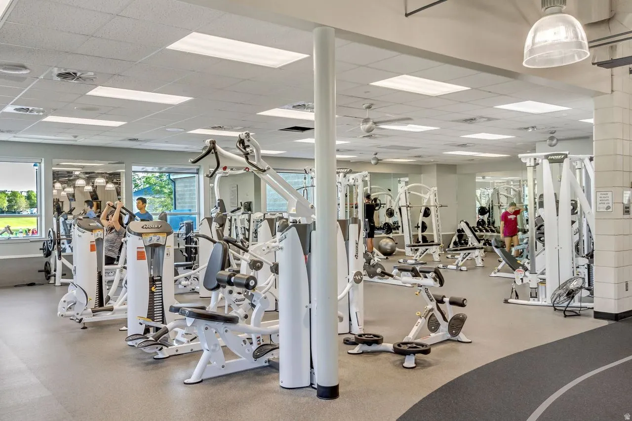 Fitness center featuring a variety of exercise equipment, mirrored walls, recessed lighting, ceiling fans, and a partial indoor track
