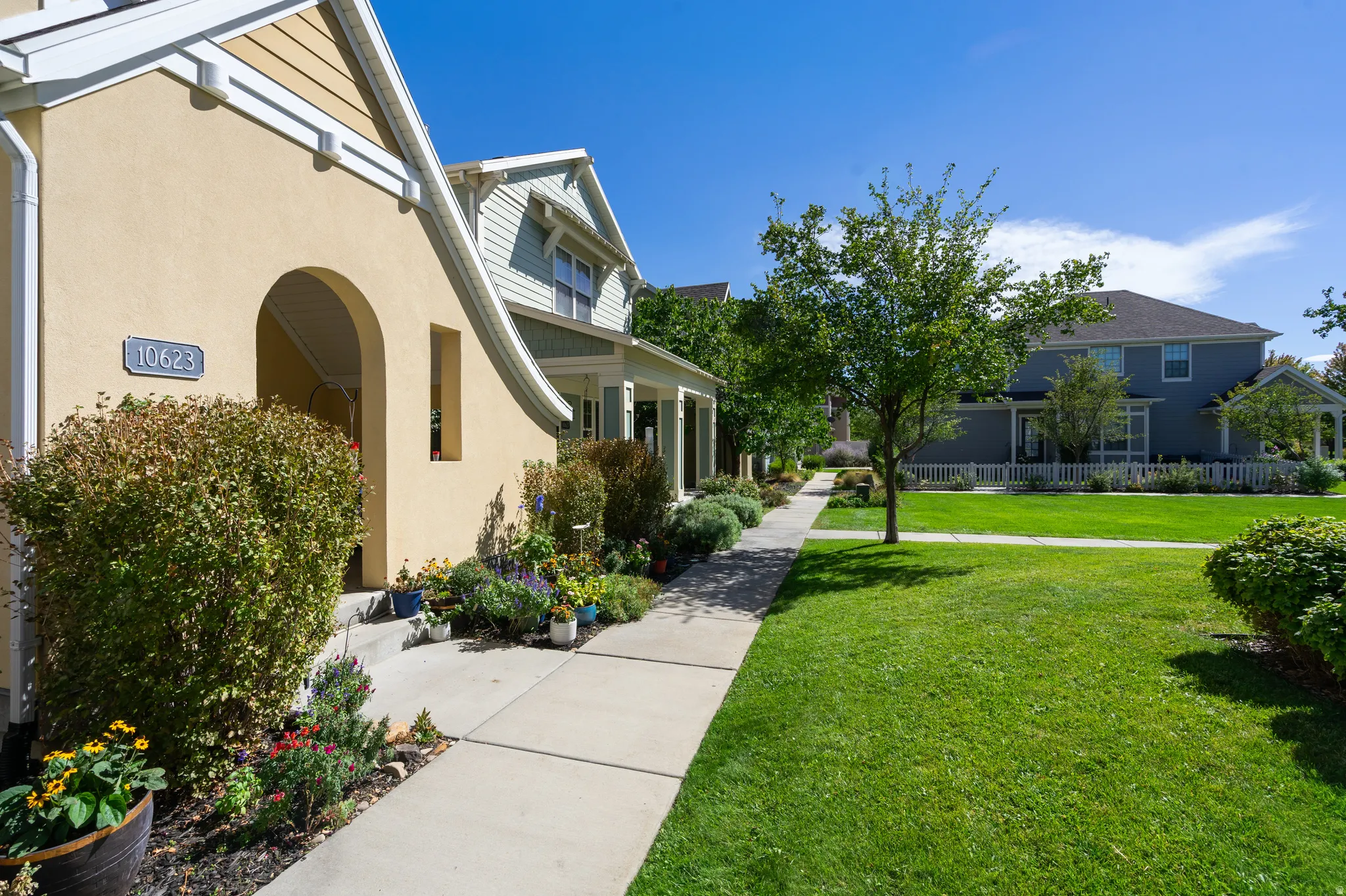Stucco exterior with an arched entry, concrete walkway, and established landscaping