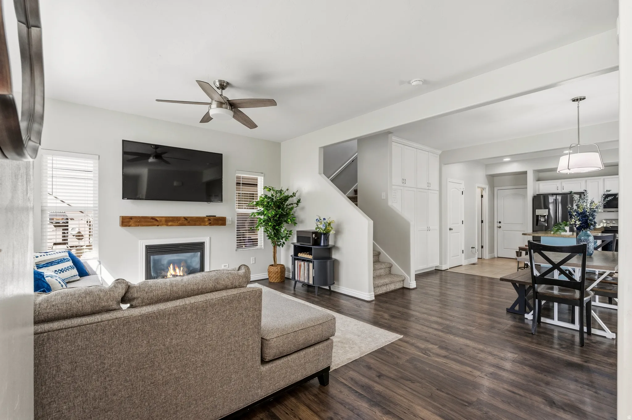 Spacious living area featuring wood-finish flooring, a fireplace with a wood mantle, and a ceiling fan