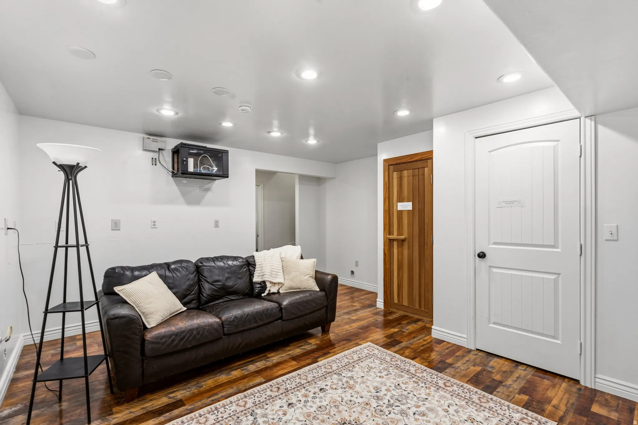 Recessed lighting, wood-finish flooring, white paneled door, and a natural wood door