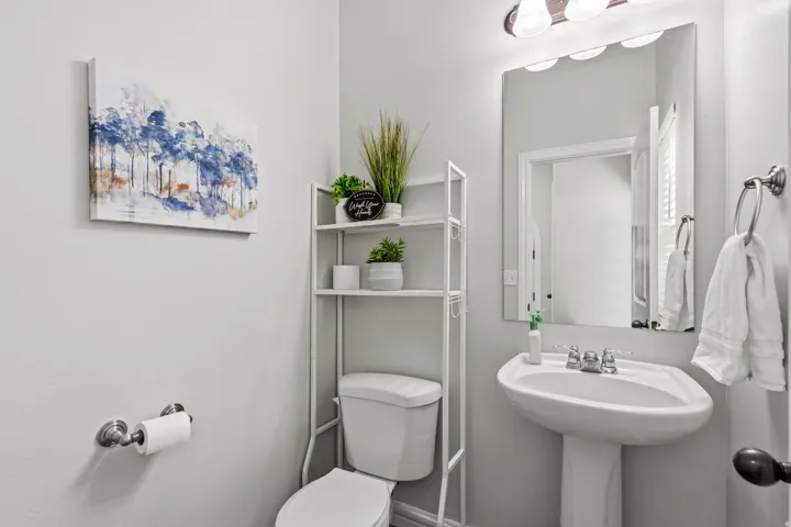 Pedestal sink with chrome-finish faucet, wall-mounted mirror, and vanity light fixture