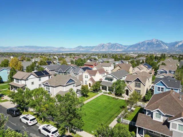 Expansive residential area with a prominent mountain backdrop, featuring a central green space, paved streets, and numerous properties with solar panels
