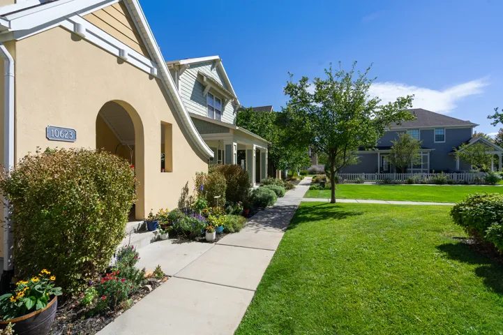 Stucco exterior with an arched entry, concrete walkway, and established landscaping