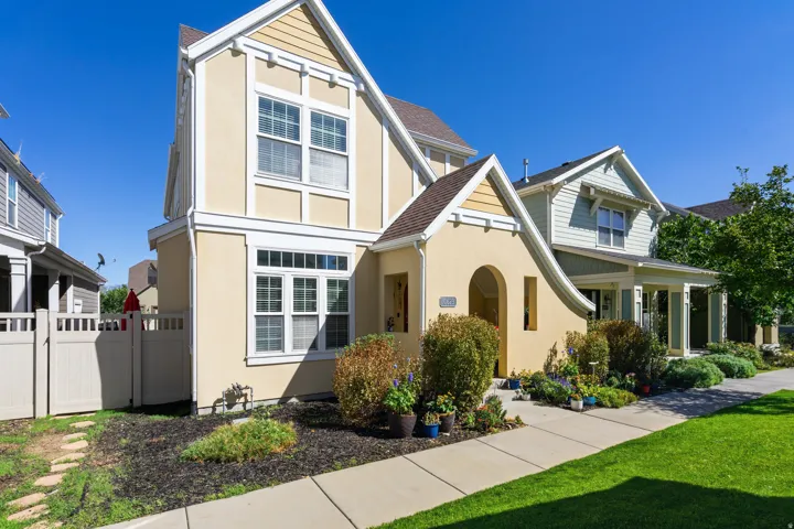 Stucco exterior with decorative trim, multiple windows, an arched entry, a sidewalk, and a manicured lawn