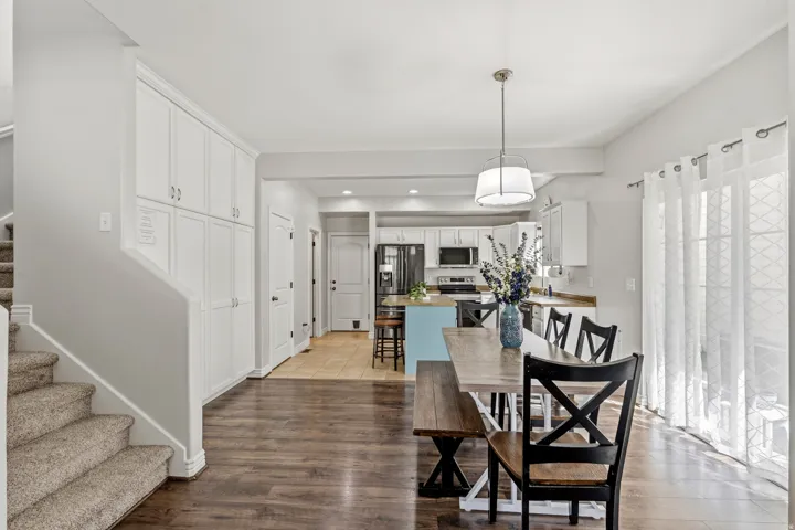 Wood-finish flooring, white cabinetry, recessed lighting, and a light-colored kitchen island with built-in appliances