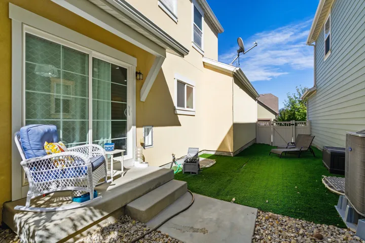Rear patio with concrete steps, sliding glass doors, and artificial turf
