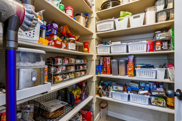 Organized pantry featuring built-in shelving with multiple tiers, integrated storage baskets, and dedicated spaces for dry goods and pantry staples