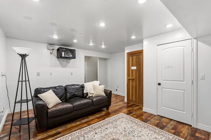 Recessed lighting, wood-finish flooring, white paneled door, and a natural wood door