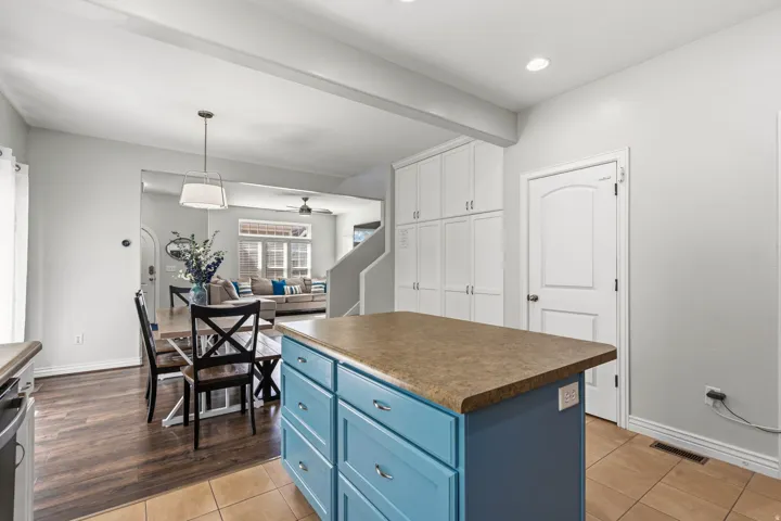 Kitchen island with blue cabinetry, neutral countertop, and tile flooring