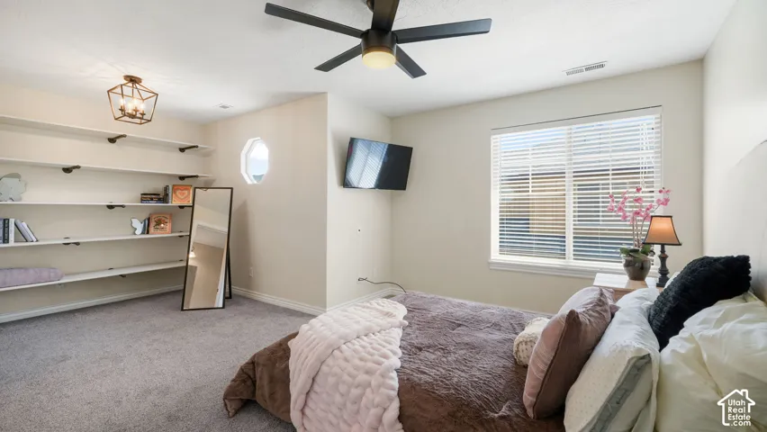 Upstairs Guest On-Suite bedroom featuring a ceiling fan, a prominent window with blinds, and a built-in shelving system