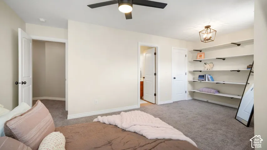 Upstairs Guest On-Suite bedroom featuring a ceiling fan with integrated lighting, a bronze-finish geometric chandelier, and built-in shelving with black metal supports