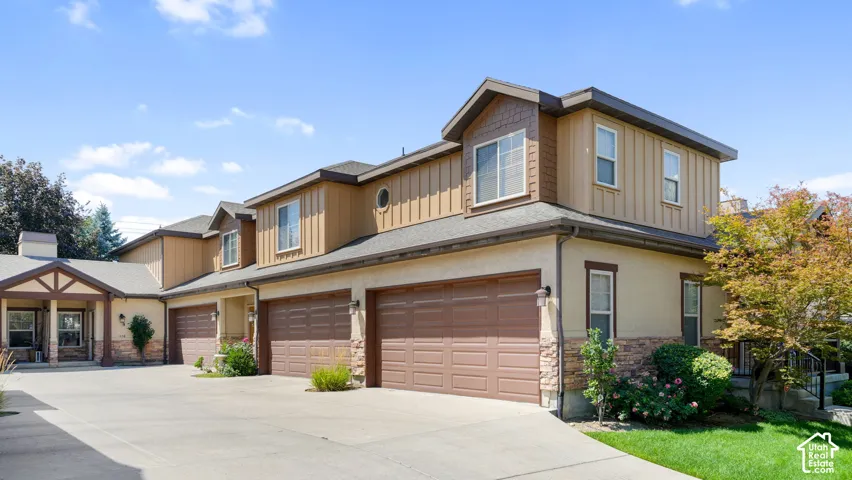 Multi-unit residence featuring stucco and vertical siding exteriors, brown garage doors, stone accents, and mature landscaping
