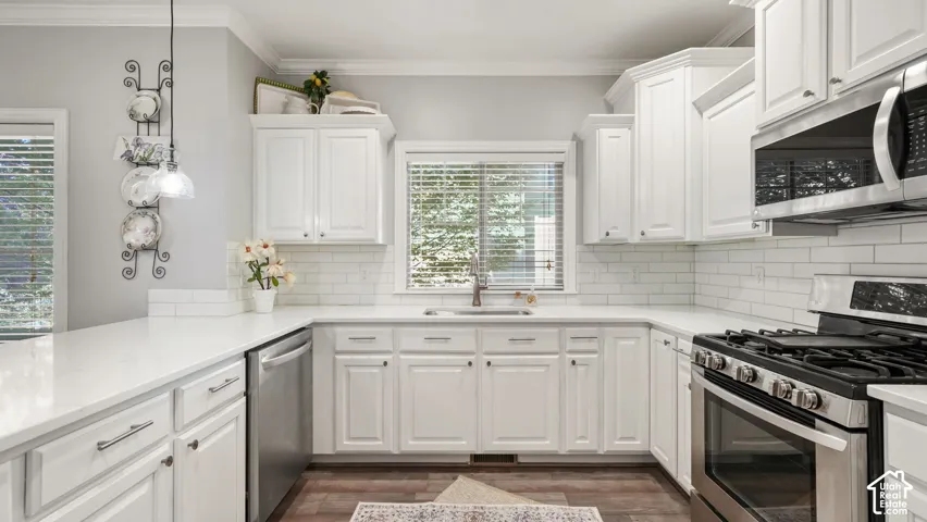 White kitchen featuring shaker-style cabinetry, stainless steel appliances, a gas range, white subway tile backsplash, and light-toned countertops