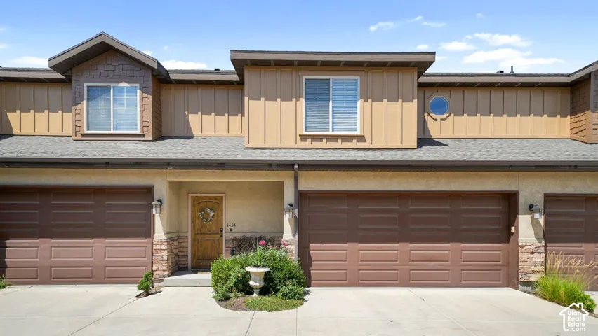 Contemporary exterior showcasing multiple gables, natural stone accents, a covered entry, and two attached garages