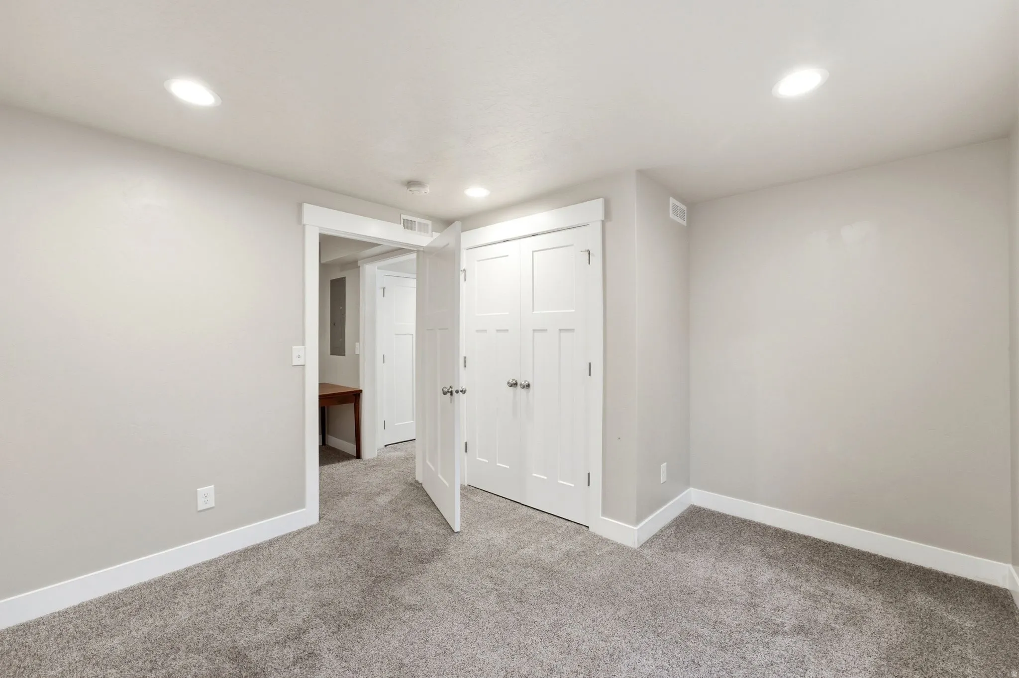 Neutral gray wall color, white trim, recessed lighting, gray carpet, and white paneled doors