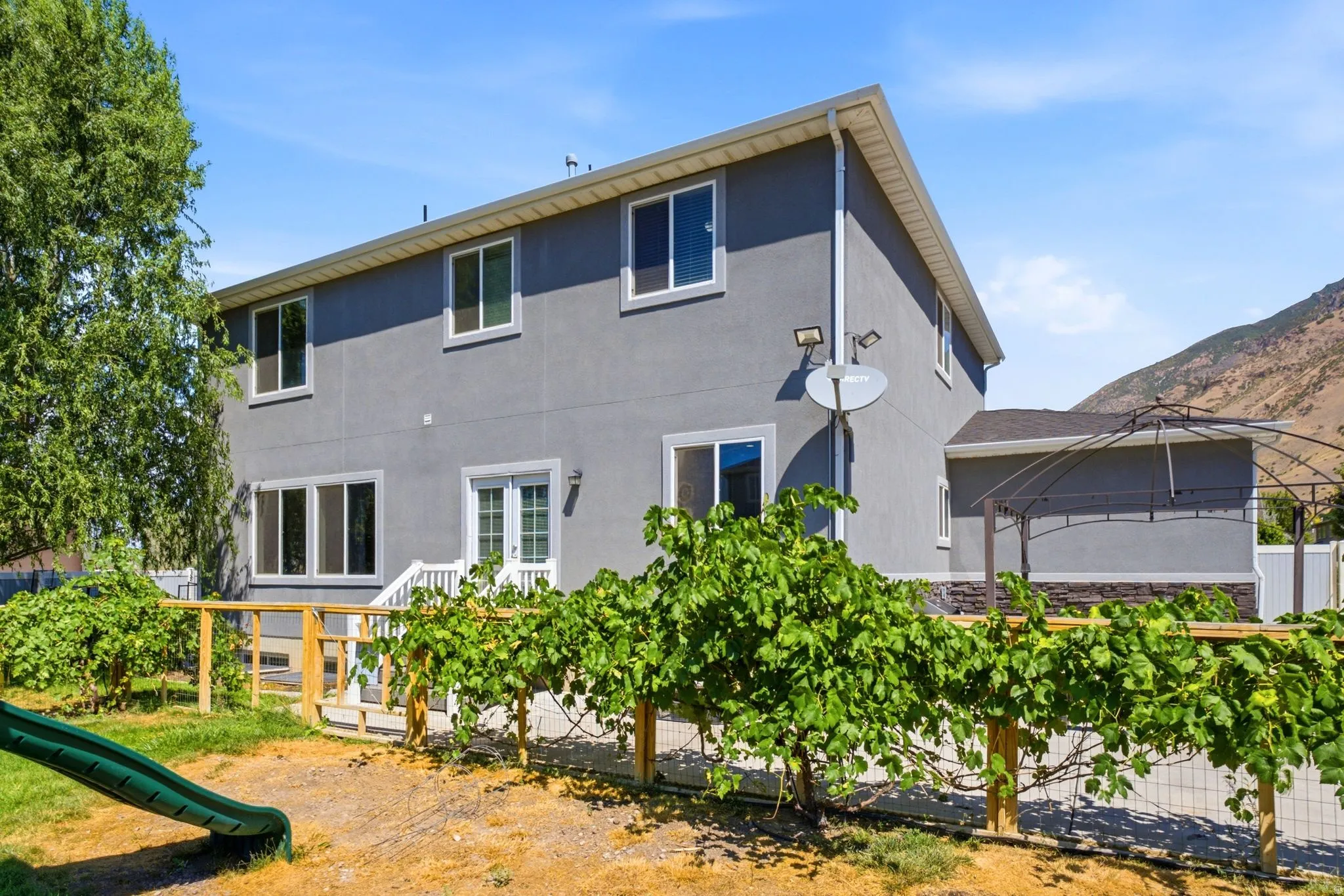 Two-story residence featuring a gray stucco exterior and white-framed windows