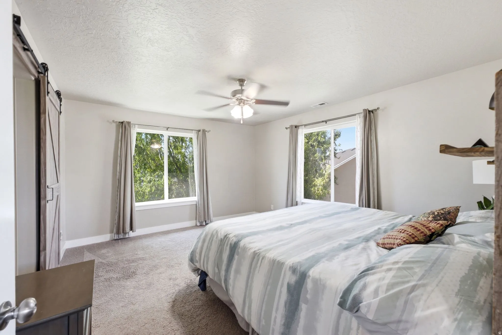 Spacious room with dual windows, neutral wall tones, and textured carpeting