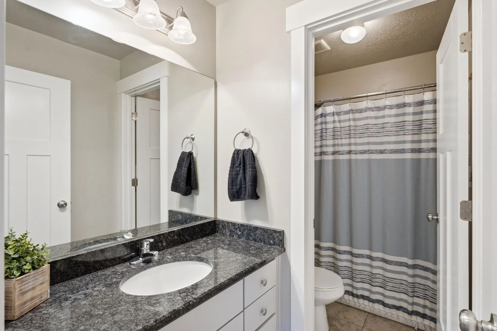 Bathroom featuring a vanity with a dark speckled countertop, white undermount sink, and chrome faucet