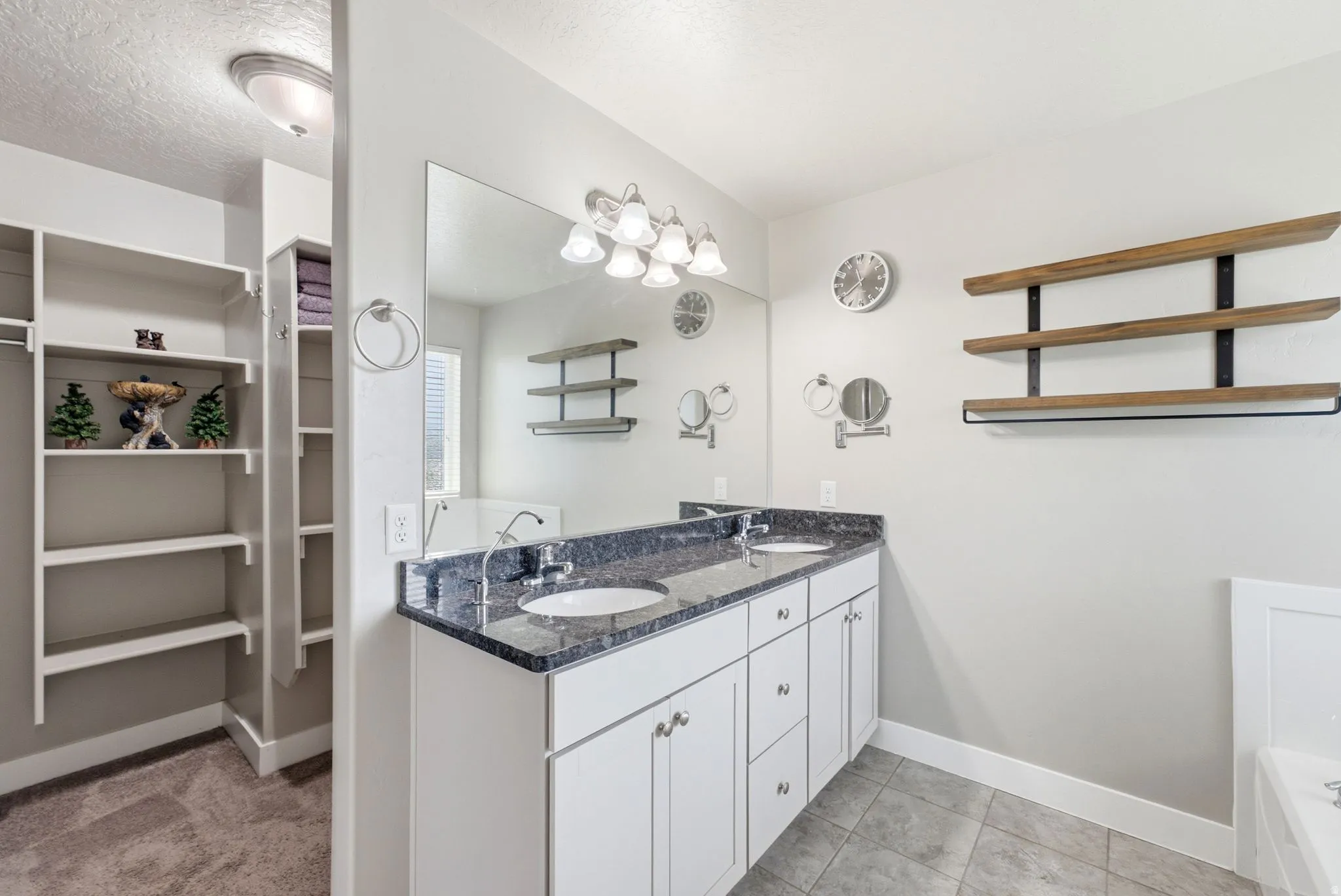 Dual vanity with white cabinetry and dark speckled countertops, undermount sinks, and a large wall mirror