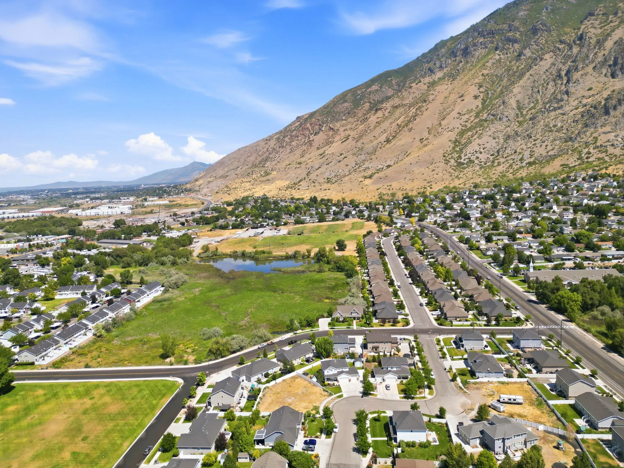 Aerial perspective showcasing a residential community with contemporary homes, a prominent mountain backdrop, and a natural pond feature