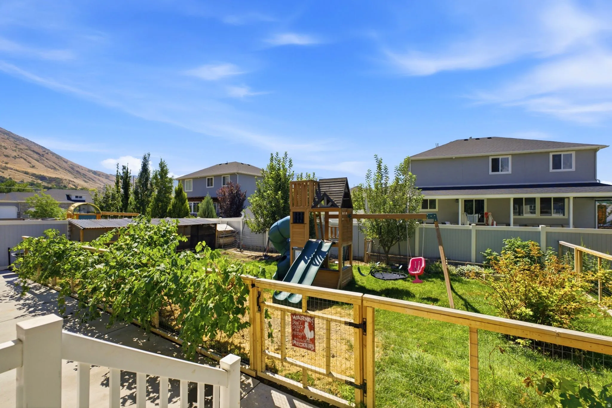 Expansive backyard featuring a lush lawn, mature trees, and a wooden fence