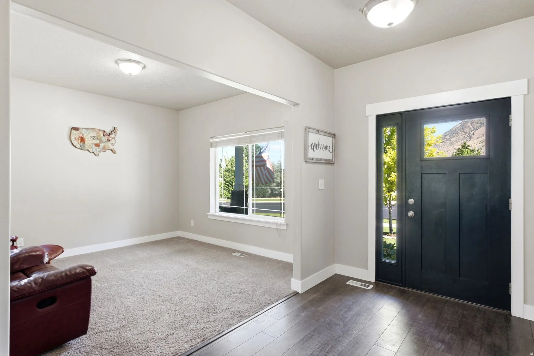 Entryway featuring wood-finish flooring, a contemporary dark wood paneled door with glass inserts, and a transom window