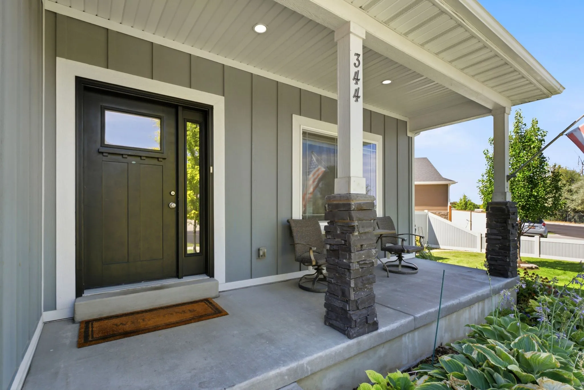 Covered front porch featuring stacked stone pillar bases
