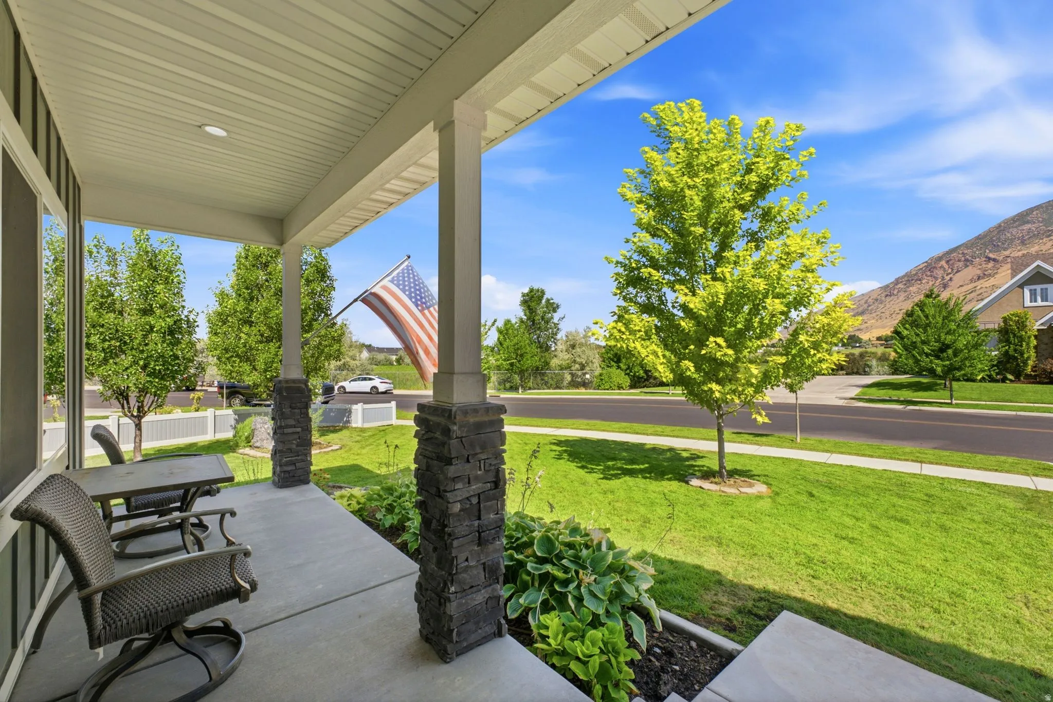 Expansive covered front porch featuring stone-clad columns and a concrete floor