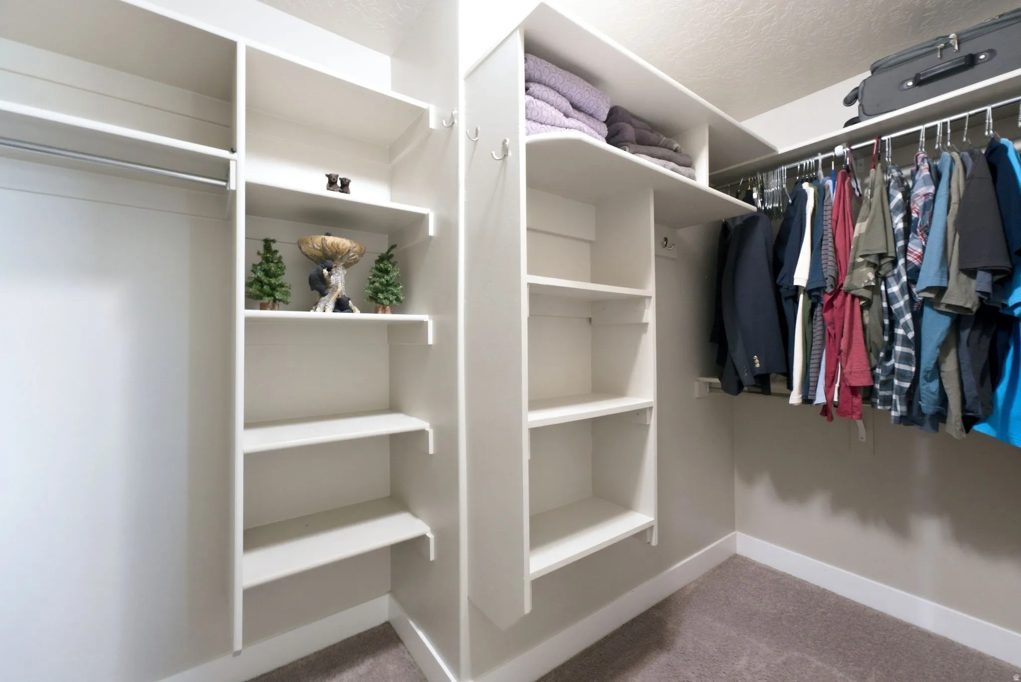 Built-in closet system featuring white shelving, multiple hanging rods, and carpet flooring