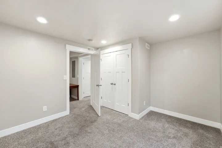 Neutral gray wall color, white trim, recessed lighting, gray carpet, and white paneled doors