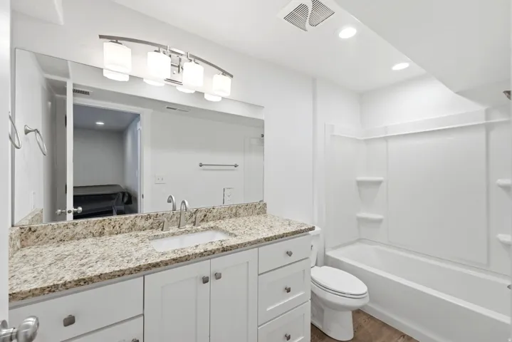Bathroom featuring a white vanity with brushed nickel hardware, granite-style countertop, and an undermount sink