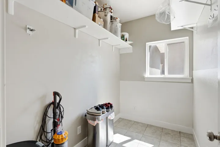 Utility space featuring light-toned walls, a white window frame, and tiled flooring