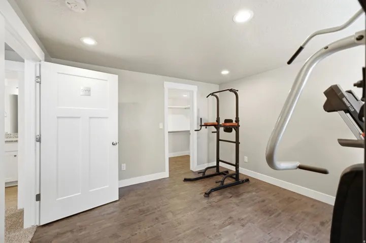 Spacious room with recessed lighting, wood-finish flooring, light gray walls, and white baseboards