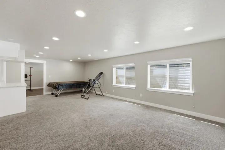 Spacious room featuring neutral carpeting, recessed lighting, and two windows with white blinds