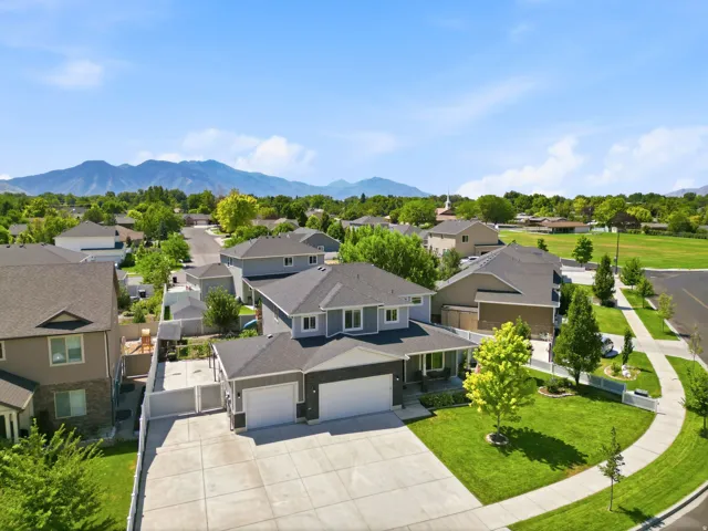 Contemporary residence featuring a two-car garage, mature landscaping, and a mountain backdrop