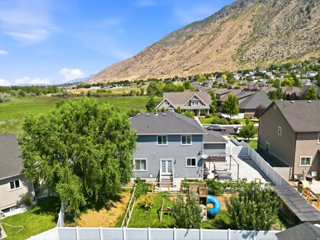 Rear exterior featuring a patio with a pergola, fenced backyard with mature landscaping, and a vibrant green lawn