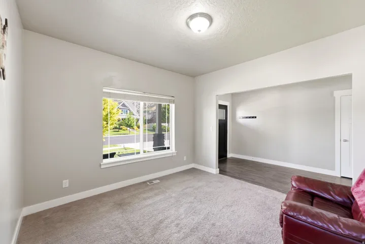 Carpeted living space featuring a large window, light gray wall paint, white baseboards, and a semi-flush ceiling light fixture