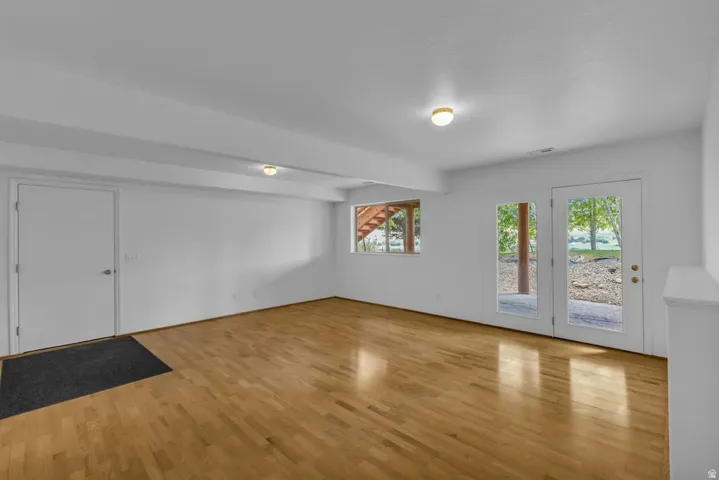 Spacious room featuring wood-finish flooring, white walls, and a white ceiling with flush-mount lighting