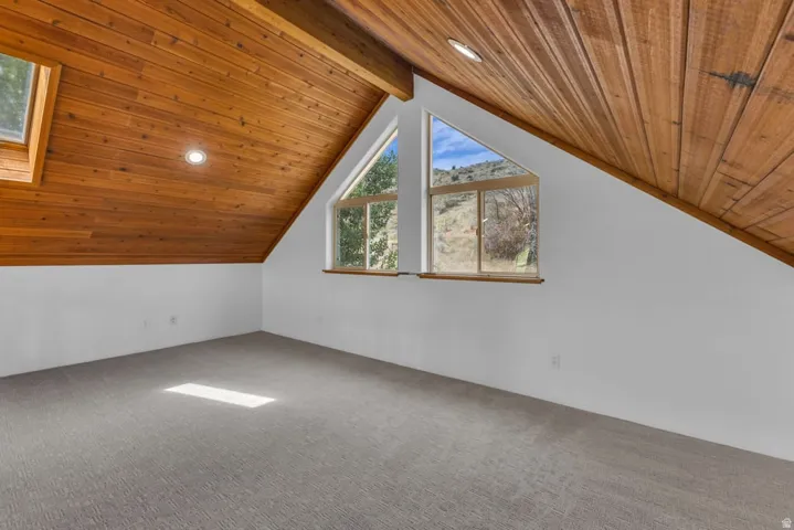 Attic space featuring a sloped wood-paneled ceiling with recessed lighting