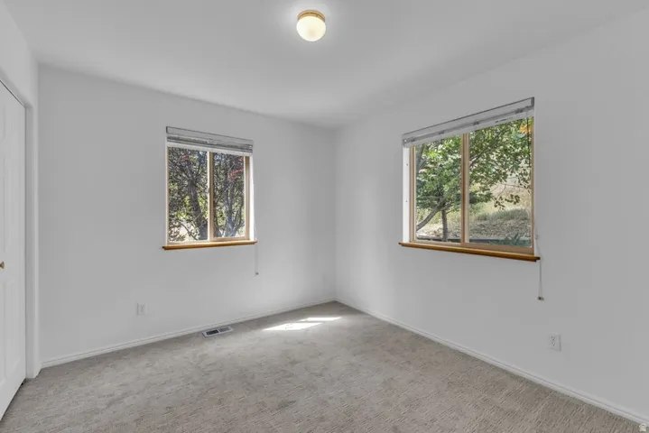 Carpeted room featuring two large windows with natural wood sills, a flush-mount ceiling light, and white walls